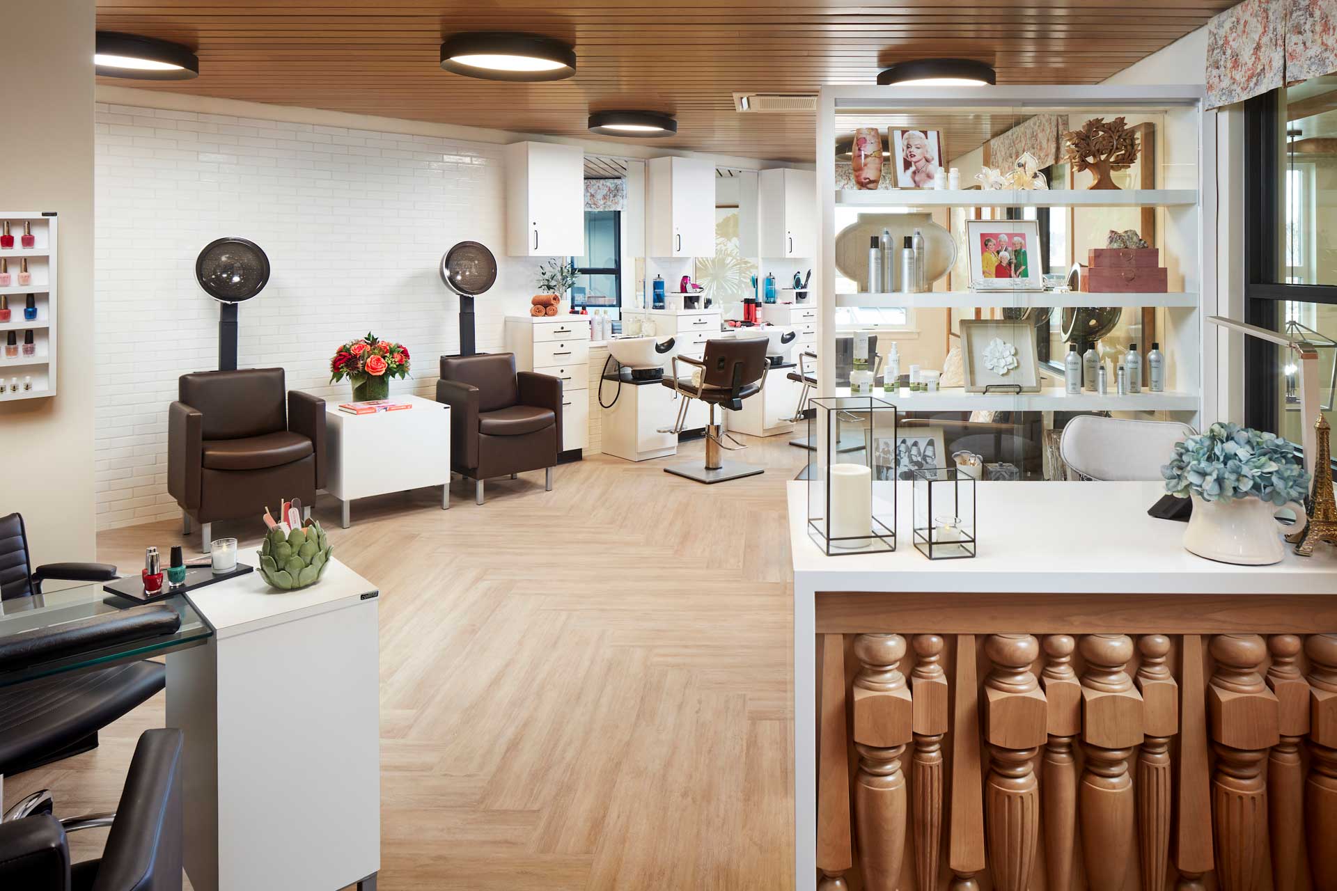 A modern salon interior at MorningStar Senior Living Kirkland features styling chairs, hair dryers, a nail station, and beauty products. The inviting space with wood floors and bright lighting is perfect for a pampering experience in retirement living.