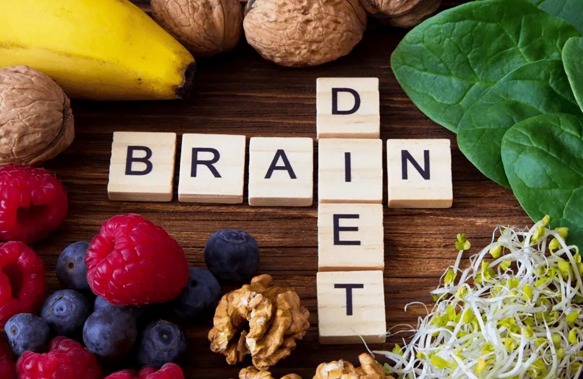 Scrabble tiles spelling “BRAIN DIET” are surrounded by healthy foods, including bananas, walnuts, spinach, raspberries, blueberries, and sprouts—reflecting the nutritious focus at Retirement Living communities like MorningStar Senior Living Kirkland.