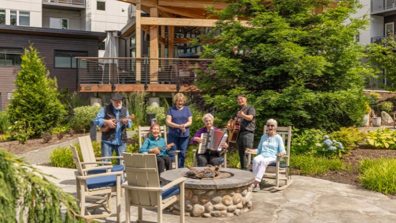 A group of seniors sitting outside playing instruments