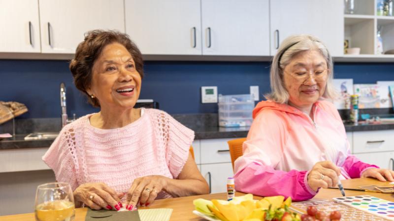 Two senior women smiling while crafting