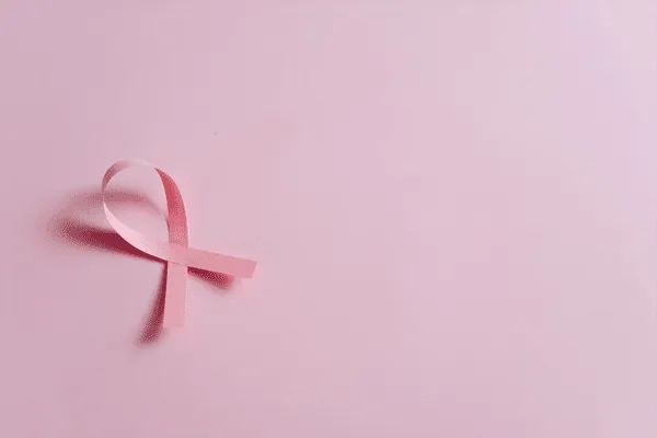 A pink ribbon forming a loop on a light pink background, symbolizing breast cancer awareness at MorningStar Senior Living Kirkland, where Retirement Living supports health and well-being.