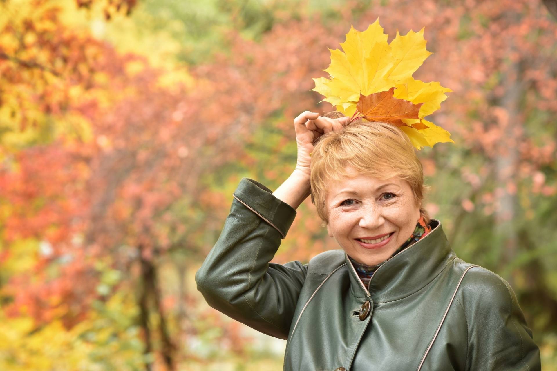 A senior woman enjoying the autumn leaves.